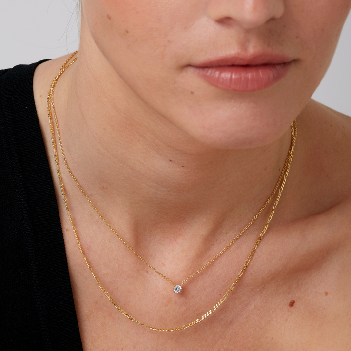 A delicate gold chain necklace with a single solitaire diamond pendant in a four-prong setting